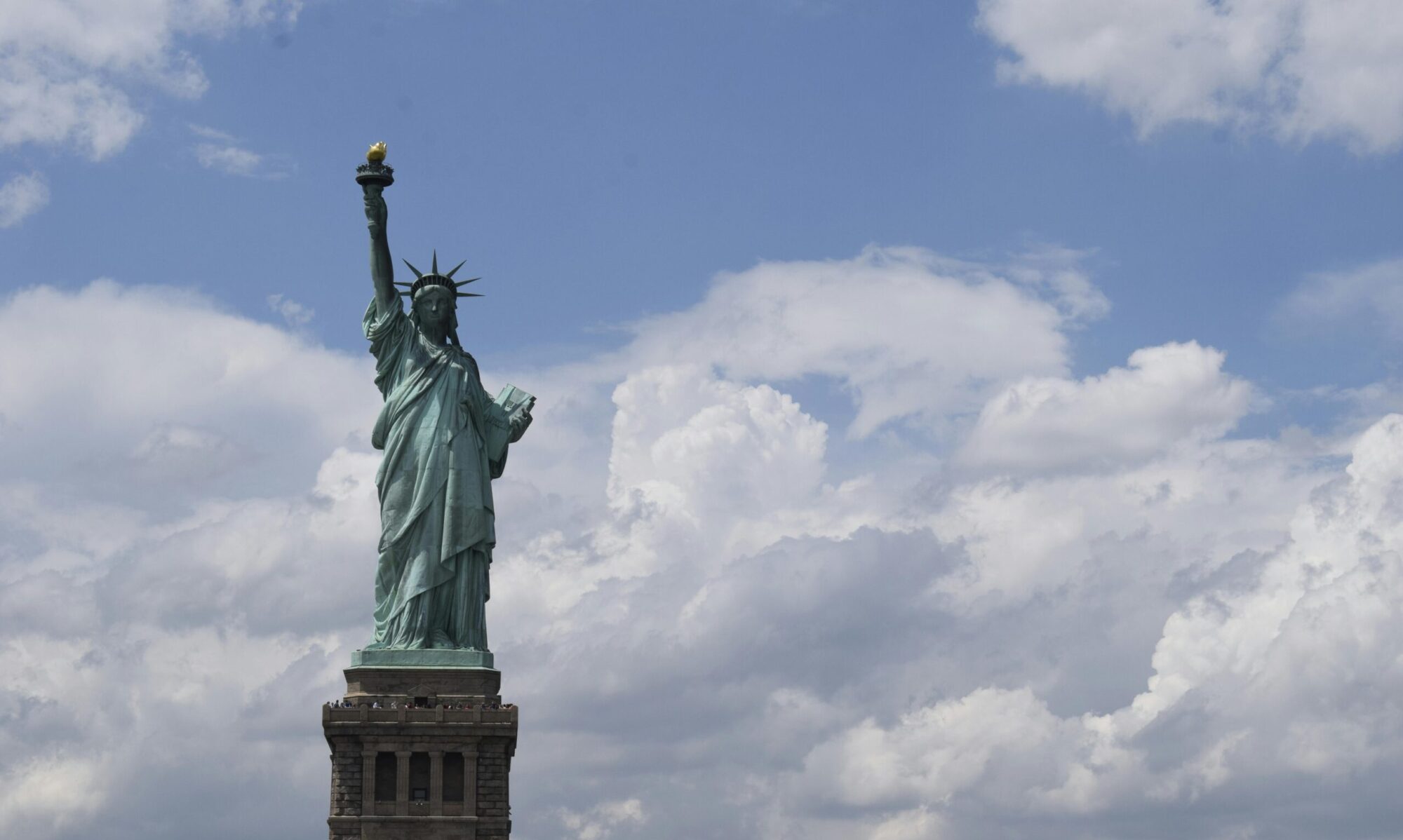 View of the iconic Statue of Liberty with a vibrant blue sky background, symbolizing freedom.